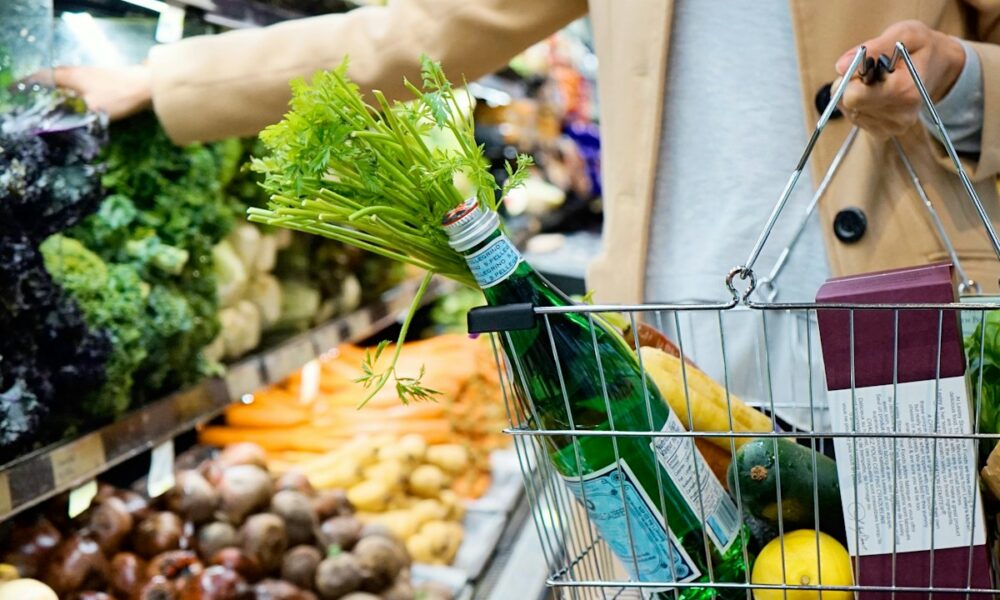woman in white coat holding green shopping cart
