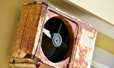 a rusted metal fan mounted to the side of a building